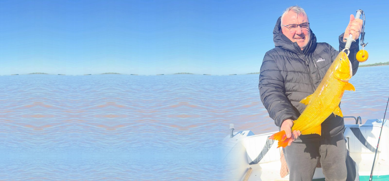 Pescador sosteniendo un dorado en la lancha sobre el río Paraná, Esquina, Corrientes