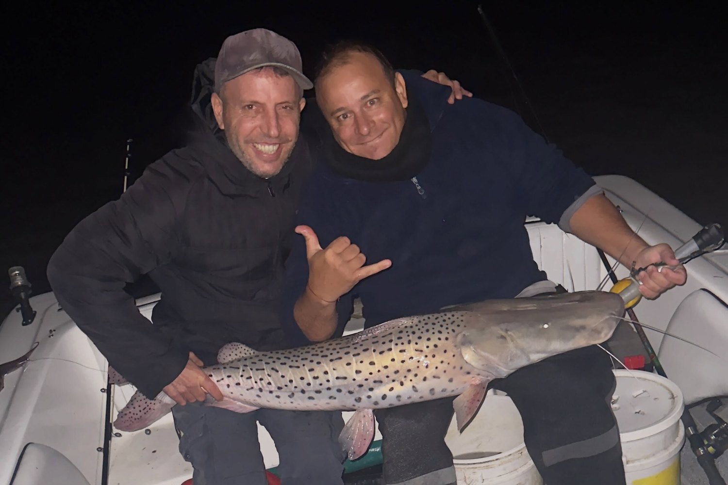 Dos pescadores con un surubí en la lancha durante una salida de pesca nocturna, Esquina, Corrientes