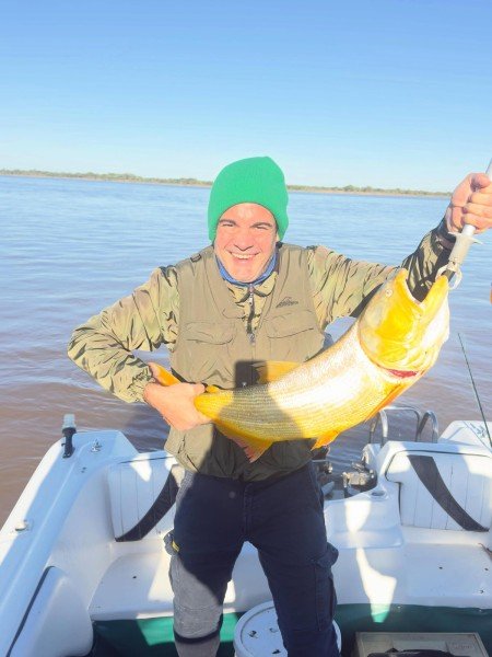 Pescador con gorro verde sonríe con un dorado en la lancha, Esquina, Corrientes