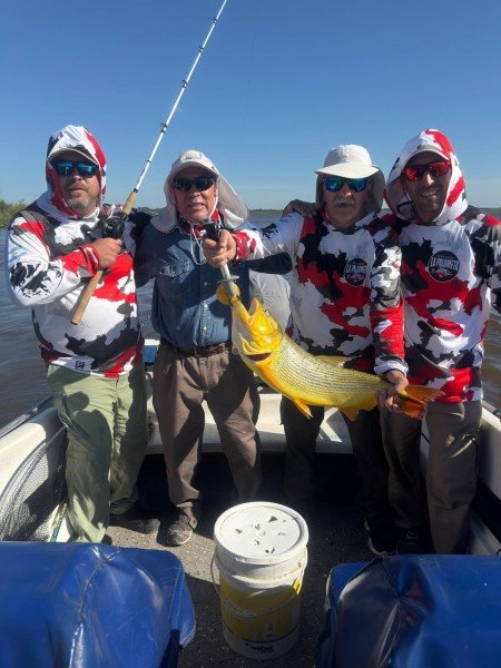 Cuatro pescadores con la misma remera sostienen un dorado, Esquina, Corrientes
