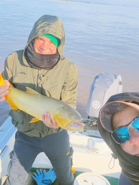 Pescador sonriente con un dorado y un amigo en primer plano, Esquina, Corrientes