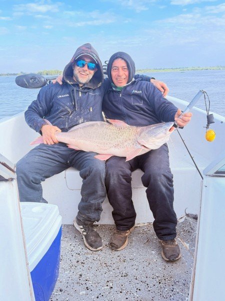 Dos pescadores sentados en la lancha con su captura, Esquina, Corrientes