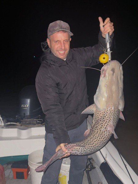 Pescador sostiene en vertical un surubí de noche, Esquina, Corrientes