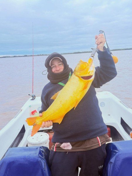 Pescador con capucha levanta un dorado en la lancha, Esquina, Corrientes