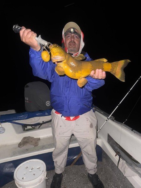 Pescador con linterna en la frente levanta su captura de noche, Esquina, Corrientes