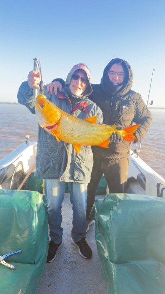 Dos pescadores abrazados con un dorado en la lancha, Esquina, Corrientes
