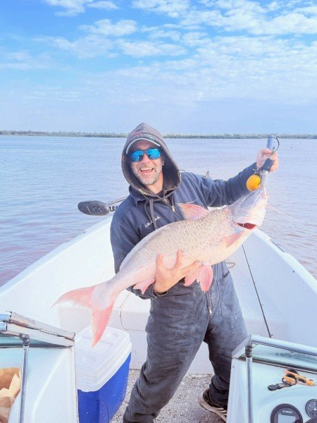 Pescador con capucha muestra una gran captura en la lancha, Esquina, Corrientes